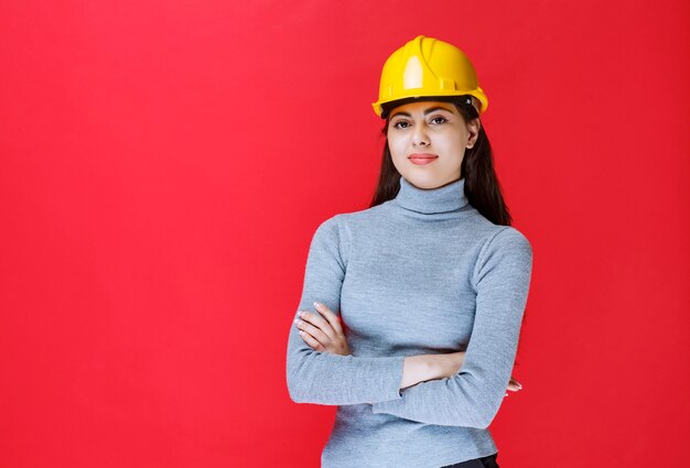 Girl in yellow helmet crossing arms and looking as a professional.