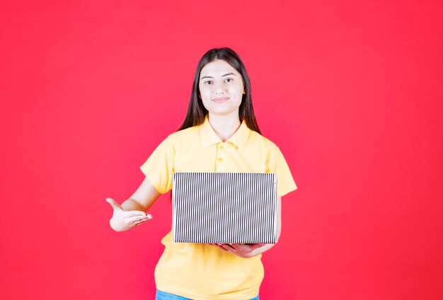 Girl in yellow shirt holding silver gift box