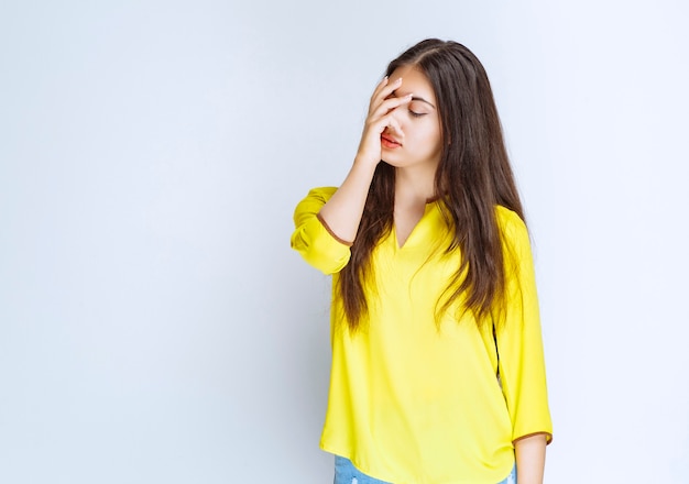 Free photo girl in yellow shirt looks tired or has headache.