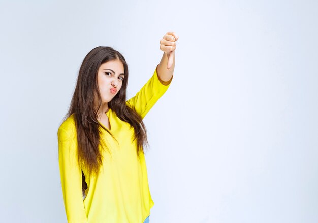 Girl in yellow shirt showing dislike sign.