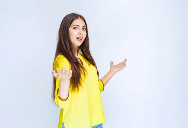 Girl in yellow shirt showing something in her open hand.