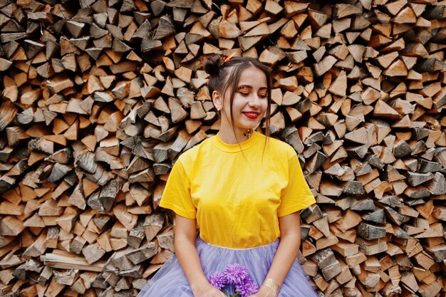 手に紫のアスターの花と黄色のシャツの女の子