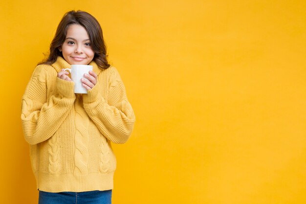 Foto gratuita ragazza in maglione giallo con la tazza in mano
