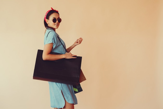 Free photo girl on a yellow wall with shopping bags