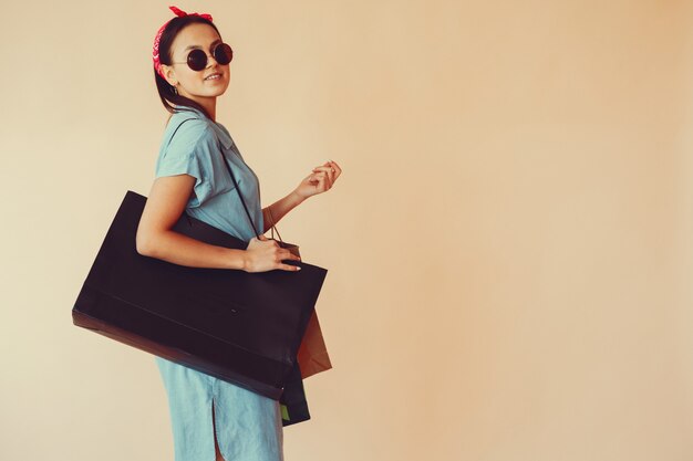 Girl on a yellow wall with shopping bags