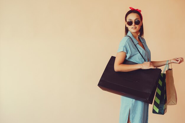 Girl on a yellow wall with shopping bags