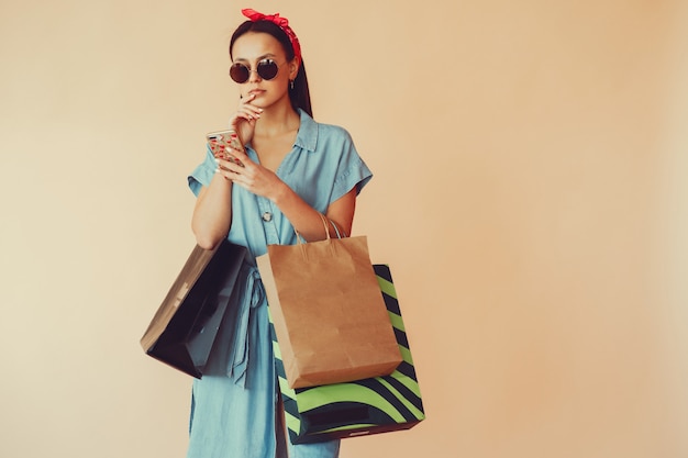 Girl on a yellow wall with shopping bags