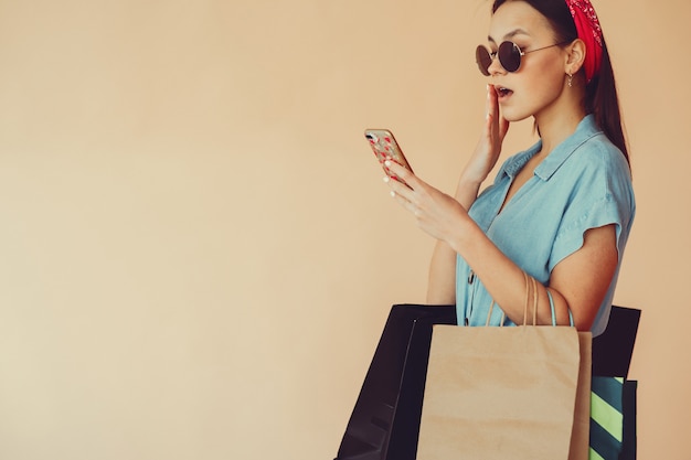 Free photo girl on a yellow wall with shopping bags