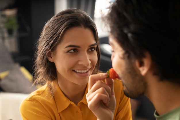 Girlfriend feeding boyfriend a strawberry at home