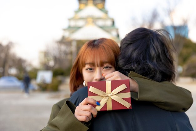 贈り物を持っている間彼女のボーイフレンドを抱き締めるガールフレンド