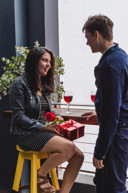Подруга улыбаясь с подарком и розой в руке