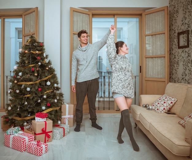 Free photo girlfriend spinning dancing with boyfriend near christmas tree