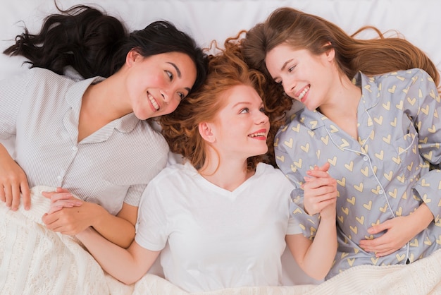 Foto gratuita le amiche giacevano a letto e tenendosi per mano