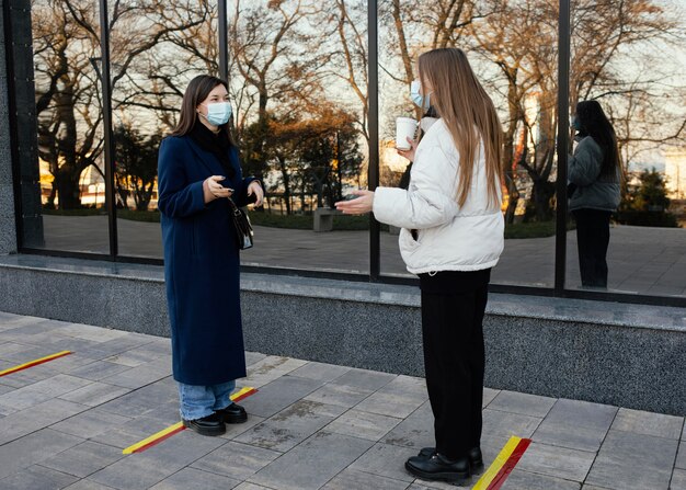 Girlfriends meeting at coffee while wearing masks