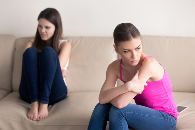 여자 친구는 소파에 앉아 격렬한 논쟁 후 서로를 미워합니다.
