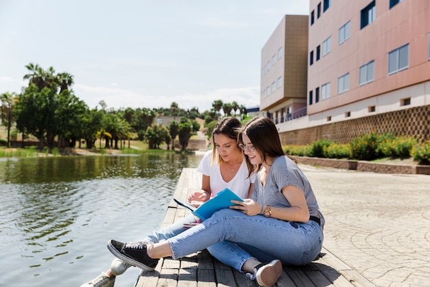 Free photo girlfriends studying in campus near lake