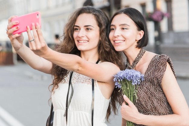 Girlfriends taking selfie with flowers