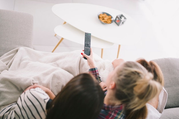 Free photo girlfriends watching tv cuddling on sofa