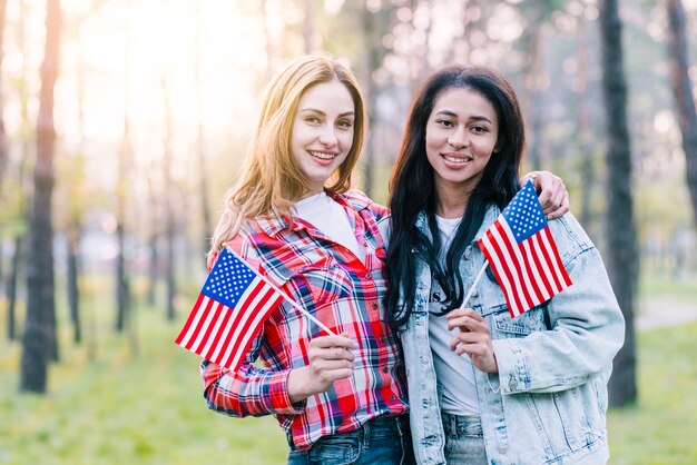 屋外に立っている小さなアメリカの国旗を持つガールフレンド