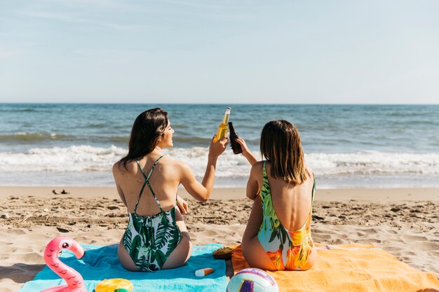 Girls at the beach toasting with beer