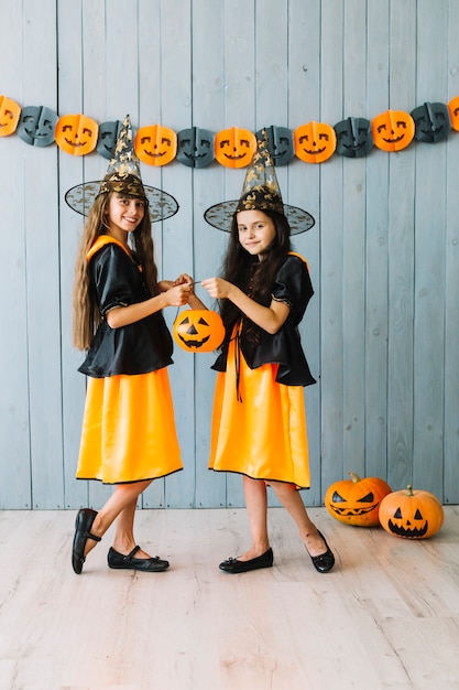 Girls in black and orange dresses holding Halloween basket 