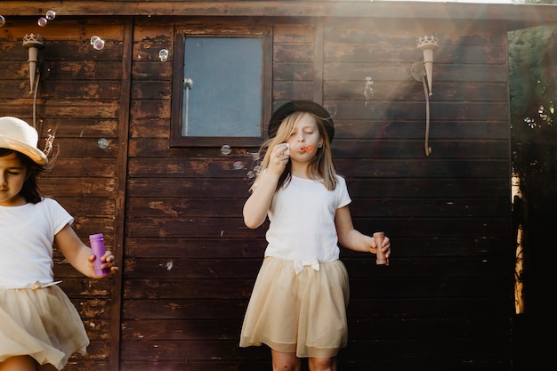 Girls blowing bubbles near wooden building
