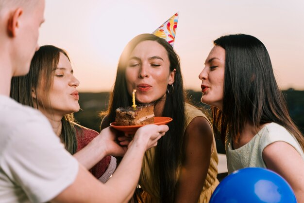 Девушки дуют свечи на день рождения торт