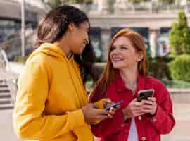 Бесплатное фото Девушки проверяют свои телефоны на улице