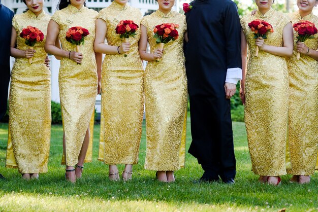 Girls in Chinese dresses with golden ornament stand around man in black