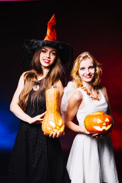 Free photo girls in costumes holding pumpkins