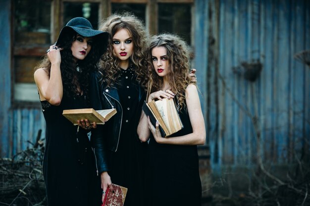Girls disguised as witches holding old books in hands