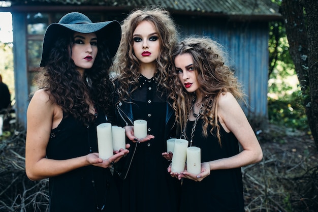 Girls disguised as witches holding white candles