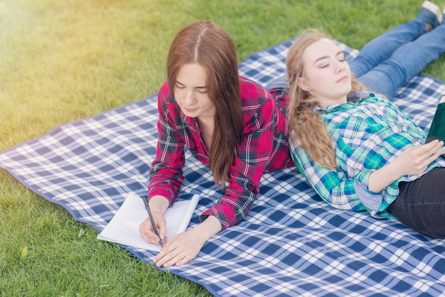 ピクニック布に宿題をしている女の子