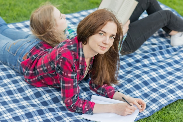 Foto gratuita ragazze che fanno i compiti sul panno da picnic