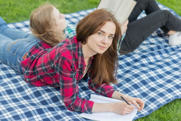 ピクニック布に宿題をしている女の子