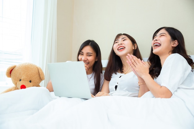 Girls group joyful looking movie on laptop together in bedroom