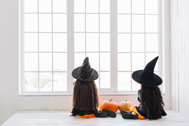 Ragazze in costumi di Halloween seduto vicino alla finestra