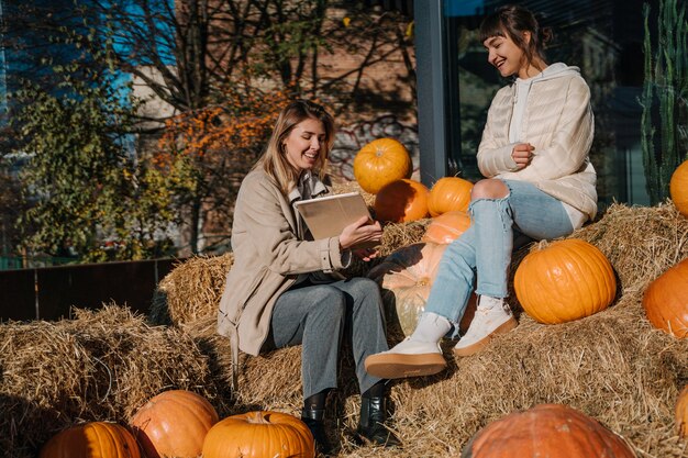 Girls have fun among pumpkins and haystacks on a city street