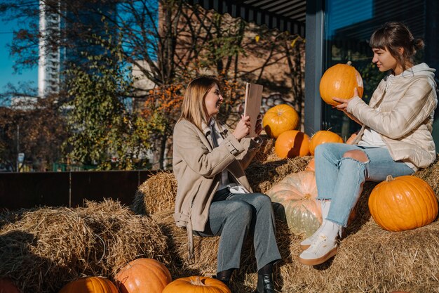 Girls have fun among pumpkins and haystacks on a city street