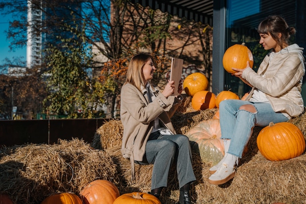 Girls have fun among pumpkins and haystacks on a city street