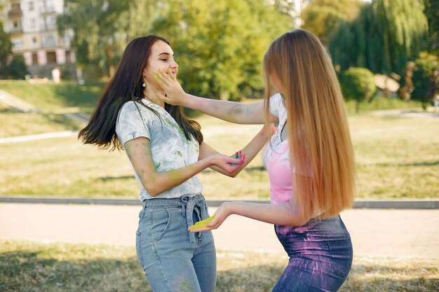 girls having fun in a park with holi paints