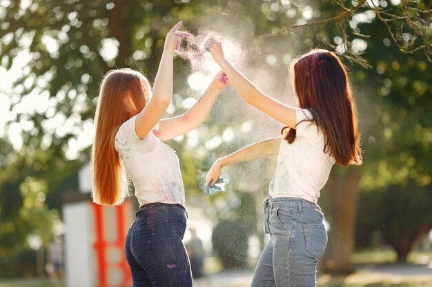 girls having fun in a park with holi paints