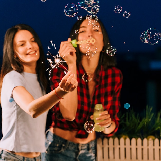 Girls having fun with soap bubbles and fireworks 