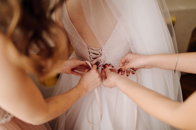 Girls helping bride to put on her dress