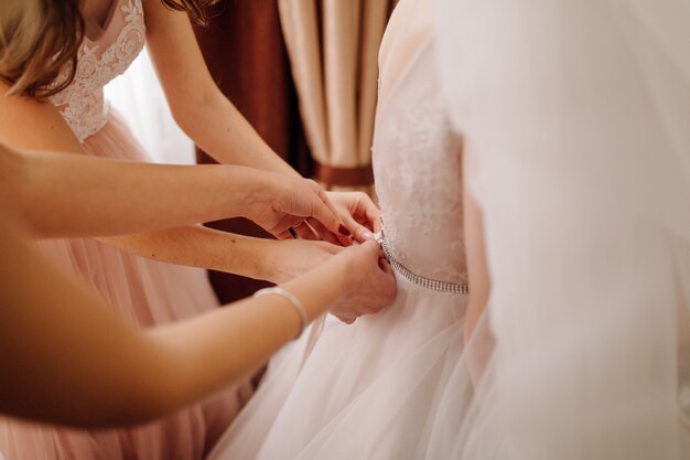 Girls helping bride to put on her dress