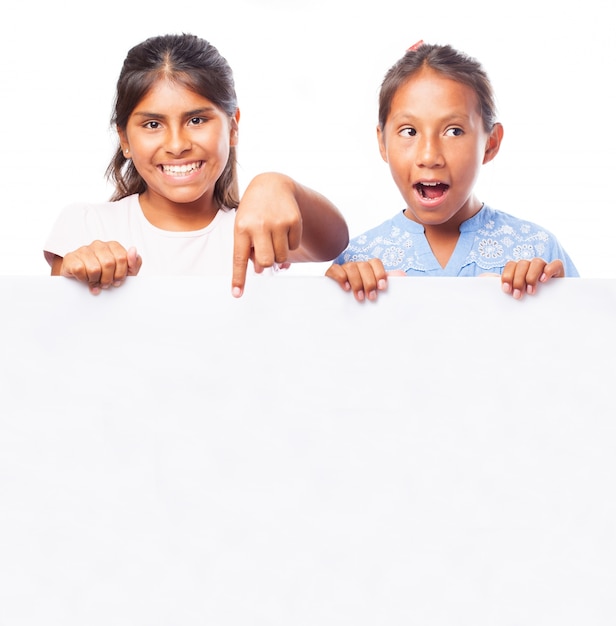 Girls holding a blank billboard and one smiling and pointing