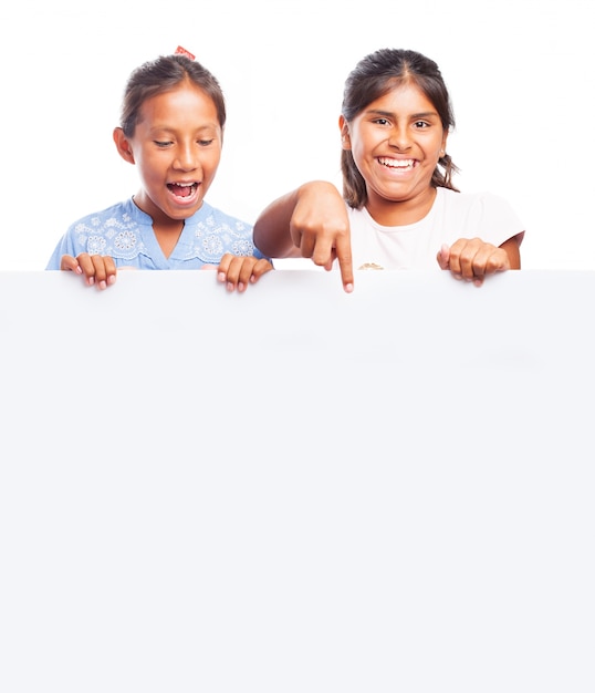 Girls holding a blank billboard and one smiling and pointing