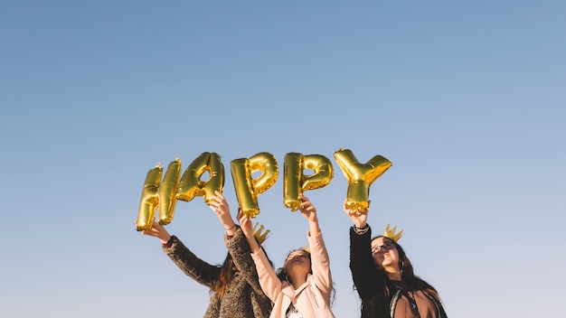 Girls holding happy writing from balloons