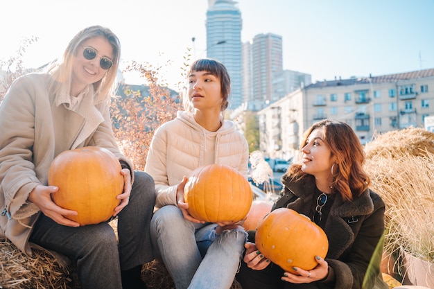 Free photo girls holds pumpkins in hands on the background of the street.