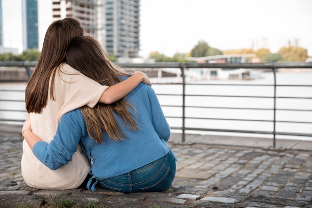 Foto gratuita ragazze che si abbracciano davanti all'acqua